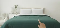 Cama de casal com roupa verde e dois almofadas brancas em quarto minimalista.