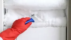Descongelar congelador com luva vermelha e raspador de gelo
